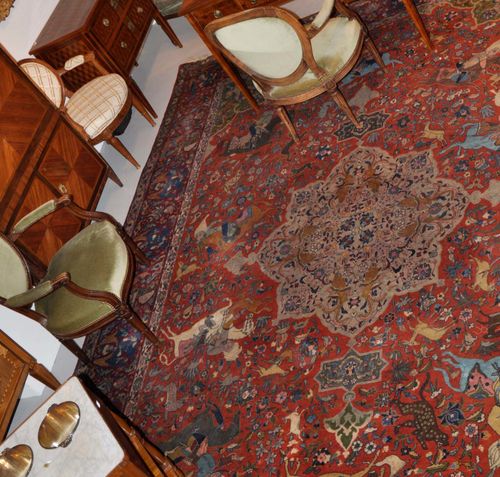 TABRIZ old.With a beige central medallion on a red ground, with green corner motifs, patterned with hunting scenes. With a red border. Slightly worn, 290x390 cm.