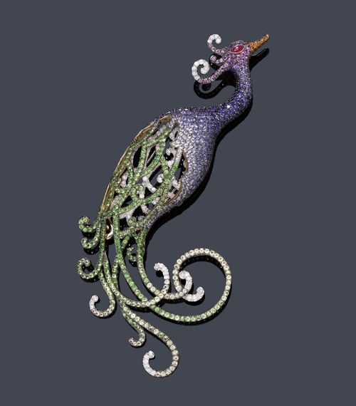 SAPPHIRE, TSAVORITE AND DIAMOND CLIP BROOCH. White gold 750. Very decorative brooch designed as a peacock, the wings set throughout with tsavorites, yellow sapphires and brilliant-cut diamonds, the body and the head set with numerous violet and blue sapphires and brilliant-cut diamonds, colour-graduated. The beak additionally decorated with orange sapphires and 1 navette-cut ruby cabochon as an eye. Total weight of the sapphires and tsavorites ca. 13.70 ct, total weight of the diamonds ca. 2.10 ct. Ca. 11 x 5 cm.