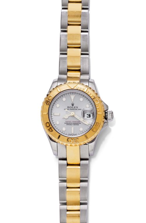 LADY'S WRISTWATCH, ROLEX YACHTMASTER, 2004. Steel and yellow gold 750. Ref. 169623. Tonneau-shaped, polished steel case No. Y146481 with rotatable gold lunette, screw-down Oyster crown and screw-down back, sapphire glass with magnifying glass. Grey dial with applied luminous indices and gold-coloured luminous hands, date at 3h. Signed: Rolex Oyster Perpetual, Date, Yacht-Master, Superlative Chronometer, Officially Certified. Automatic, movement No. 1498426, Cal. 2235. Matte-finished and polished steel-gold Oyster band with fold-over clasp. D 29 x 35 mm. With case, instructions and warranty, December 2004.