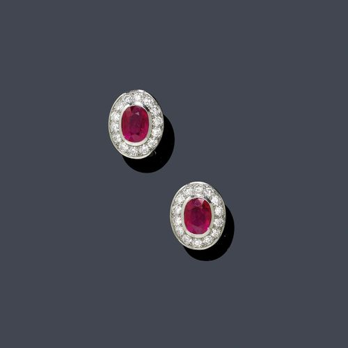 RUBY AND DIAMOND EAR CLIPS. Platinum 950 and white gold 750. Decorative ear clips with studs, each set with 1 oval ruby weighing 3.12 ct and. 3.06 ct, respectively, treated, each within a border of 14 brilliant-cut diamonds. Total weight of the diamonds ca. 2.60 ct. With GRS Report GRS2005-080209, August 2005 and copy of invoice, 2006.