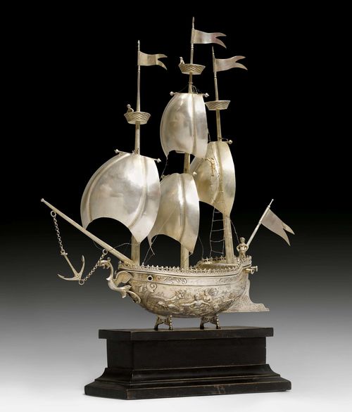 HISTORIC GOBLET DESIGNED AS A SHIP, ON A WOODEN PLINTH,probably The Netherlands or Belgium, 20th century. With mythological scenes from the Kingdom of Neptune. Billowing sails of silver sheet, fine ropes of silver wire. Hull and deck, marked.  H including base ca. 52 cm.