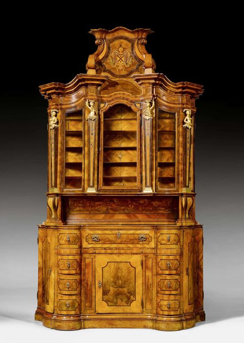 VITRINE CABINET "AUX FEMMES PORTEUSES", Baroque, probably Main-Franconia um 1720. Walnut, burlwood and local fruit woods, exquisitely inlaid with coat-of-arms cartouche, probably of the family VALLENTINI in Dalmatia - fillets and decorative frieze. Curved, trapezoid body with stepped top with cartouche. Some losses. 3 glass doors flanked by gilt caryatids. Top cover of lower part missing. 177x62x293 cm. Provenance: - from a private collection in Southern Germany. - Semenzato Auction, Venice, 4 March 1990 (Lot No. 104). - from a European collection.
