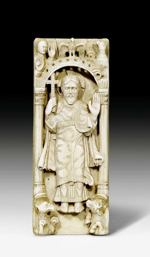 IVORY PLAQUE,in Romanesque style, German, 19th century. Ivory carved in half relief. Standing Christ figure with a cross in the right hand and the left hand raised in blessing. In a fine, columned niche with the symbols of the 4 evangelists. Verso with label "Laroussilhe Paris". H 13 cm. Provenance: former Raoul Heilbronner (1847-1941) collection, Paris.