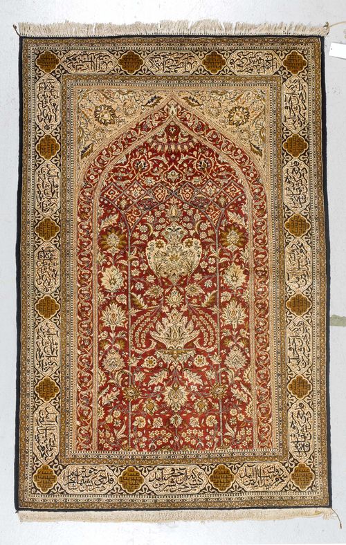 GHOM SILK old.Red mihrab with beige spandrels, opulently patterned with plant motifs in harmonious colours, light border with inscription cartouches, in good condition, 140x213cm.