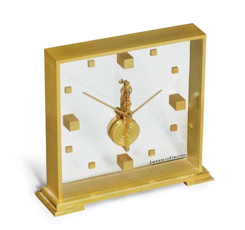 TABLE CLOCK WITH STICK MOVEMENT, JAEGER LE COULTRE, ca. 1980. Brass. Square, glass-covered brass case No. 553 with visible, vertical movement. Signed on the glass. Stick movement, Cal. 210/1. Ca. 15 x 15 cm, without base. With copy of the warranty, December 1979.
