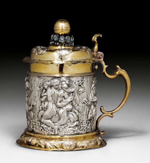 TANKARD WITH COVER,probably Nuremberg circa 1700. Maker's mark not identified. Parcel gilt. Cylinder form with chased and embossed stand ring. The wall with relief decoration on all sides with bathing nudes and mermaids between reeds. H 22 cm.1102 g.