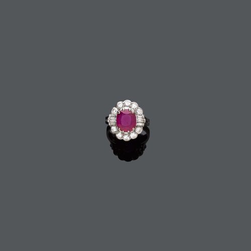 BURMA RUBY DIAMOND RING, ca.1950. White gold 750. Set with an antic oval-cut Burma ruby of ca. 3.25 ct, flanked by baguette-cut and brilliant-cut diamonds, weighing ca. 1.00 ct. Size ca. 53.