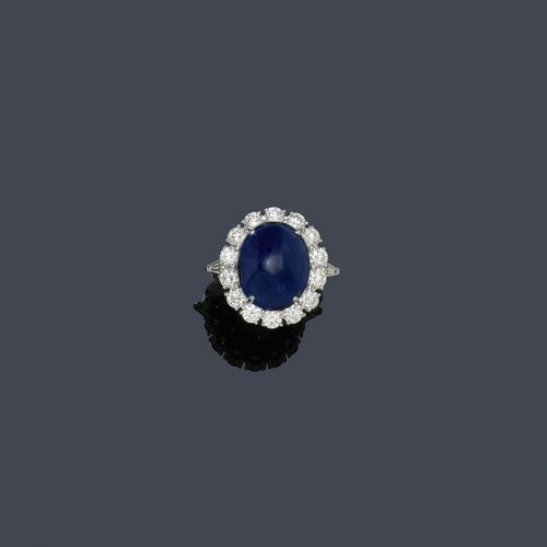 BURMA SAPPHIRE AND DIAMOND RING. White gold 750. Classic-modern ring, the top set with 1 fine, royal-blue, Burma sapphire cabochon of 10.57 ct, untreated, within a border of 14 brilliant-cut diamonds and flanked by 2 trapeze-cut diamonds. Total diamond weight, ca. 1.45 ct. Size ca. 54. With GRS Report No. GRS2009-11071T, November 2009.