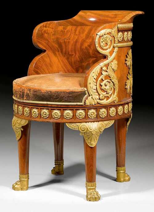 MAHOGANY FAUTEUIL DE BUREAU "MINISTRE",Empire style , from a Paris master workshop, 19th century. Shaped mahogany pivoting seat with columnar legs and paw feet. With worn brown leather covers and exceptionally rich matte and polished gilt bronze mounts and applications. 50x50x51x80 cm. Provenance: from a French collection