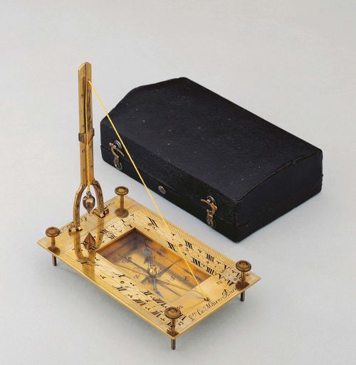 A HORIZONTAL TABLE SUNDIAL IN CASE, Paris, circa 1735. Sign. LE MAIRE PARIS. Gilt bronze. Rectangular ground plate with 2 engraved dials (6-12-6) and inscribed A MR. DE ST. MESMIN. Compass with windrose, and blued needle. String gnomon with plumb line. Verso with numerous pole heights of cities. In with black leather covered case with red velvet lining, 13x8.2x3.3 cm.