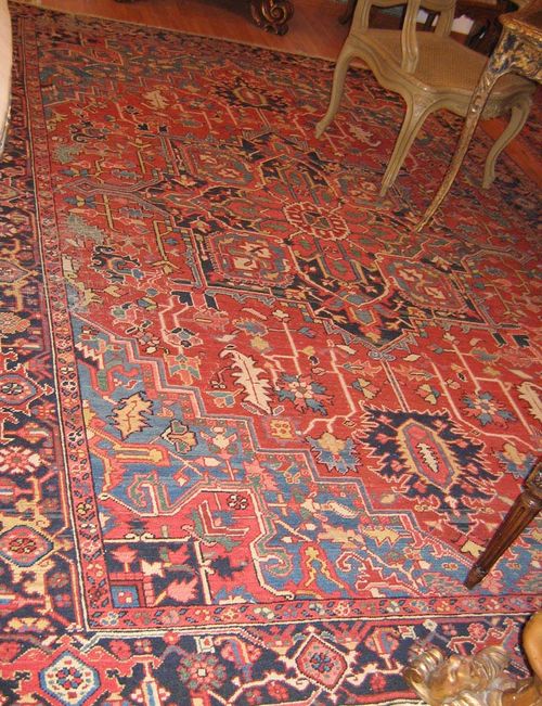 HERIZ old.Red ground with a central medallion, blue corner motifs, typically patterned, black border, signs of wear, 306x218 cm.
