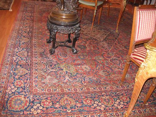 KESHAN old.Red ground with a blue central medallion, the entire carpet is finely patterned with floral motifs in harmonious colours, blue border, slight wear, 405x310 cm.