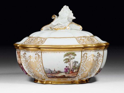 IMPORTANT TUREEN WITH LANDSCAPE SCENE, Meissen, circa 1745.Painted on all four sides with merchant scenes and park landscapes together with gold lattice panels. The domed lid with rocaille finial. Underglaze blue sword mark . D 31cm. Hair crack. The gilding on the edge retouched.