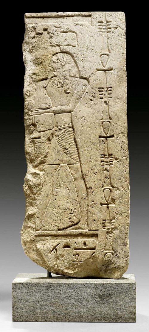 EGYPTIAN FRAGMENT,probably New Kingdom, 19th/20th Dynasty, 1250-1100 BC. Limestone. Standing deity, next to a frieze of the good-luck symbols for "Djed" (stability) and "Ankh" (life), with additional hieroglyphics above/below. On modern granite plinth. H 64 cm.