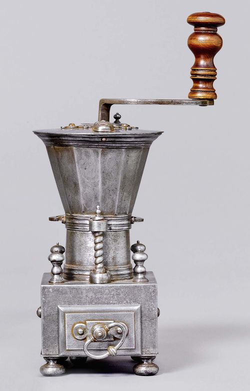 A TABLE TOP COFFEE MILL, France, circa 1700. the inside of the lid marked R.MARTIN. Cone-shaped hopper on rectangular body with drawer for grinds. The screw clamp with fleur-de-lys decoration. H 28 cm. Rare and early example.