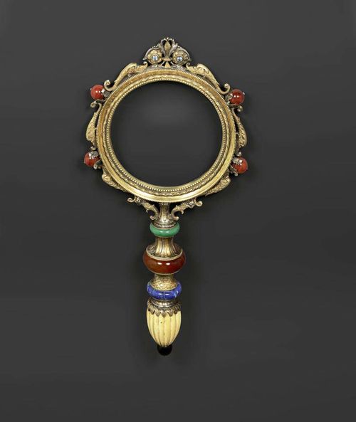 IMPORTANT MAGNIFYING GLASS,Renaissance style, after the so-called "Medici magnifying glass" from the 17th century, Italy, 19th century. Vermeil and various gemstones - carnelian, lapis, aventurine and zircon - and ivory. L 38 cm,  glass D 13 cm. Provenance: -Palazzo Serristori, Florence. -West Swiss castle collection.