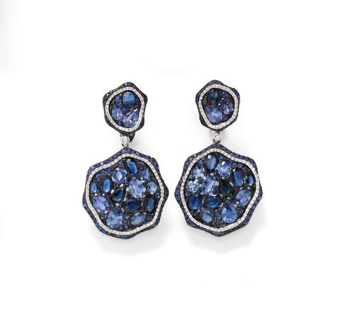 SAPPHIRE AND DIAMOND EAR CLIPS. White gold 750. Decorative ear clips with studs consisting of 2 flexibly connected elements, each set with 36 sapphires in different shapes, sizes and shades of blue, within a border of diamonds and sapphires. Total weight of the sapphires ca. 16.00 ct, total weight of the diamonds ca. 0.60 ct. L 4.5 cm.