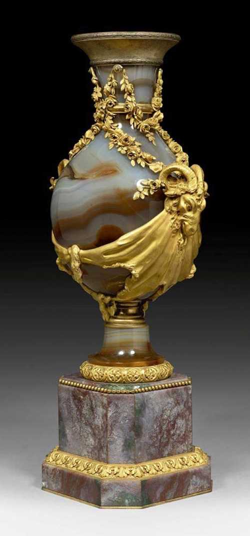 AGATE VASE "AUX TETES DE BELIERS" WITH BRONZE MOUNTS,late Louis XVI, Paris, 19th century. White/brown agate, wine red quartz with white, grey and green, and matte and polished gilt bronze. Exceptionally fine gilt bronze mounts and applications. H 45.5 cm.