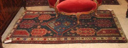 KAZAK old.Blue central field with large medallions in red and blue, with stylised plants and stars. White border. Both sides slightly shortened, slightly worn. 210x117 cm.