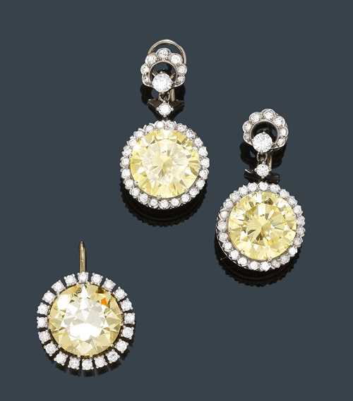 DIAMOND EAR PENDANTS AND PENDANT, ca. 1950. White gold 750. Elegant ear clips with studs, each of a round pendant set with a brilliant-cut diamond of 10.20 ct, Z/VS2* and 9.42 ct, Z/ VS1*, respectively, within a border of brilliant-cut diamonds, flexibly mounted on a clip part set with brilliant-cut diamonds. Total weight of the 64 brilliant-cut diamonds ca. 1.30 ct. Matching, round pendant set with a brilliant-cut diamond, older cut, of 11.81 ct, Y/ VS2 within a border of brilliant-cut diamonds weighing 0.40 ct. With Gemlab Reports Nos. 2330/09, 2332/09 and 2329/09. * Potentially IF after recutting.