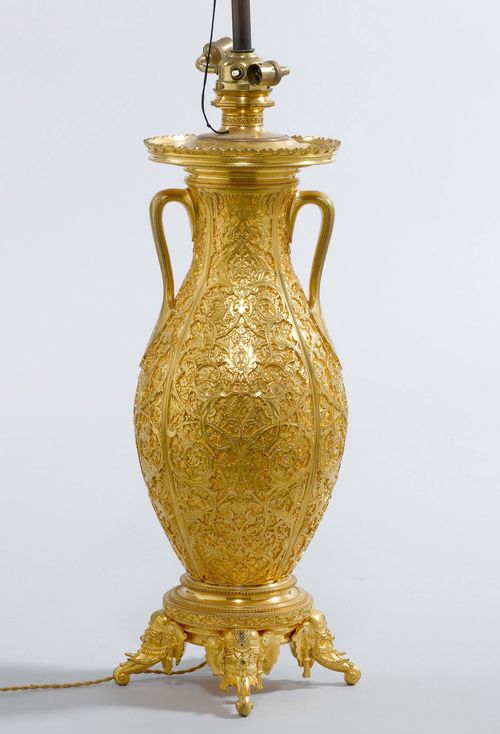 LAMP, France,probably Barbedienne. Gilt bronze. Vase-shaped, with 2 handles and protruding lip. Finely chiselled walls and tendril and flower decoration. On 4 feet designed as elephant heads. H 85 cm.