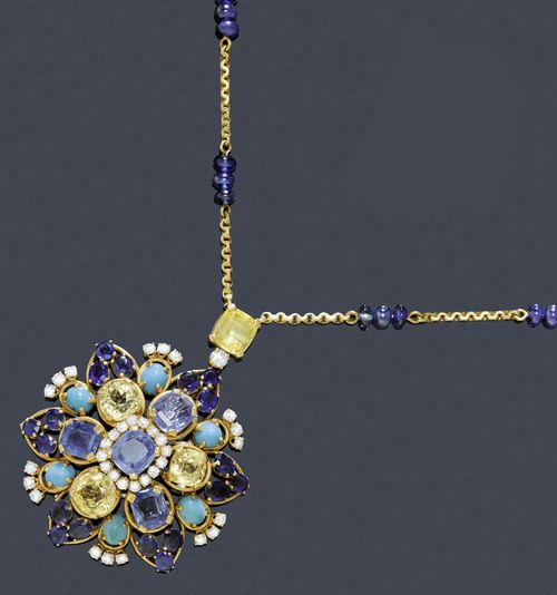 A SAPPHIRE, TURQUOISE AND DIAMOND NECKLACE VAN CLEEF & ARPELS, circa 1970. Yellow and white gold 750. Stylish clip brooch / pendant modeled as a stylized flowerhead set in center with 1 Ceylon sapphire of ca. 4.00 ct in brilliant-cut diamond surround of ca. 0.80 ct, encircled with 3 yellow and 3 blue sapphires of a total of ca. 20.00 ct surrounded by 6 oval turquoise cabochons, 18 oval sapphires of a total of ca. 10.00 ct and 18 brilliant-cut diamonds of a total of ca. 1.00 ct. Signed Van Cleef & Arpels, no. 90976. On a delicate curb chain with 48 sapphire rondelles as spacers, the attache set with 1 yellow sapphire of ca. 4.00 ct and 1 brilliant-cut diamond of ca. 0.23 ct, no. 90976. Sapphire untreated, slight signs of wear. L ca. 63 cm.