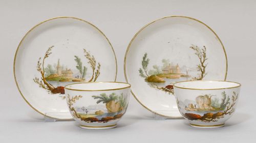PAIR OF TEA CUPS AND SAUCERS WITH LANDSCAPE VIGNETTES,Nyon, ca. 1781-1813. Each piece painted with a lake landscape, gold edges. Underglaze blue fish marks. Gilding, slightly rubbed. (4) Provenance: Private collection, Geneva.