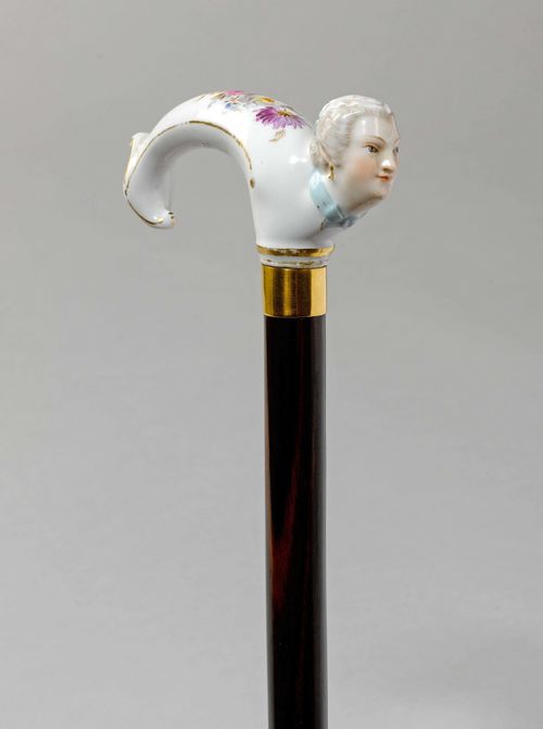 WALKING STICK WITH PORCELAIN HANDLE,German, probably Meissen. Curved handle with head of a woman and bouquet of flowers. Gold ring, ebony stick, bone tip. L 95.5 cm.
