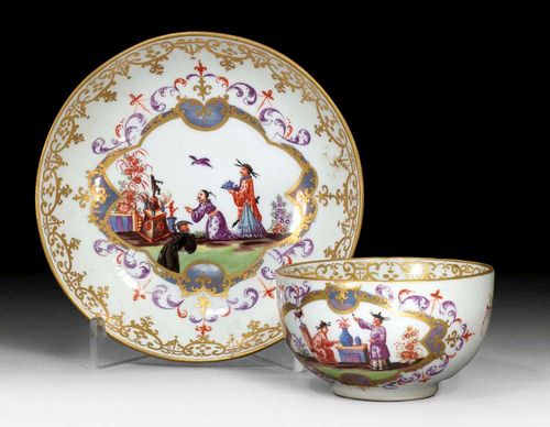 CHINOISERIE DECORATED CUP AND SAUCER, Meissen, circa 1780-1815.Each piece with a chinoiserie scene in the tradition of J.G.Höroldt in gold cartouche. Foliate decoration in purple and iron red. Gold border. The cup with Indianischen Blumen to the side of the handle. Underglaze blue sword and star. A 33 and A13 impressed.