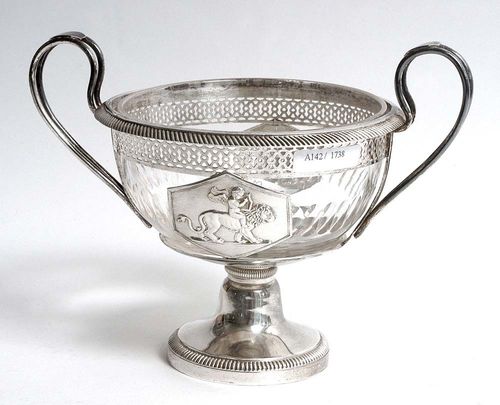 FOOTED BOWL WITH GLASS LINER. Lausanne, circa 1820.Maker's mark  Frères Gély. The foot with gadrooned edge, with cut glass liner set in an openwork holder, the front and back decorated with a plaque enclosing a putto riding a lion. H 13 cm.