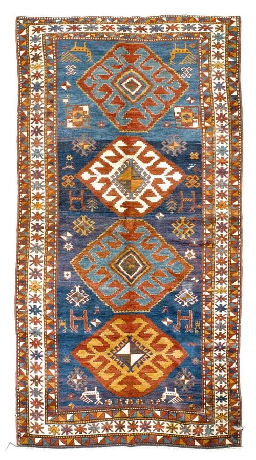 KARS KAZAK antique.Blue central field with four medallions, geometrically patterned with plants and animals, stepped border, minor damage, otherwise in good condition, 305x155 cm.