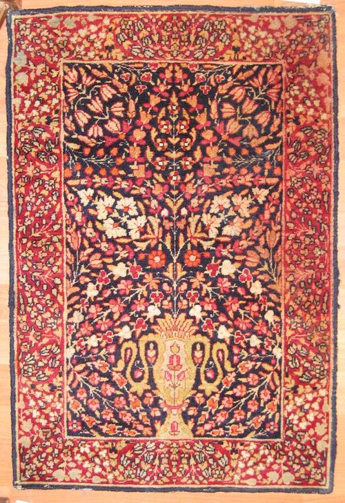 SMALL KIRMAN RAVER antique.Blue central field with a vase, red border, slight wear, 75x50 cm.