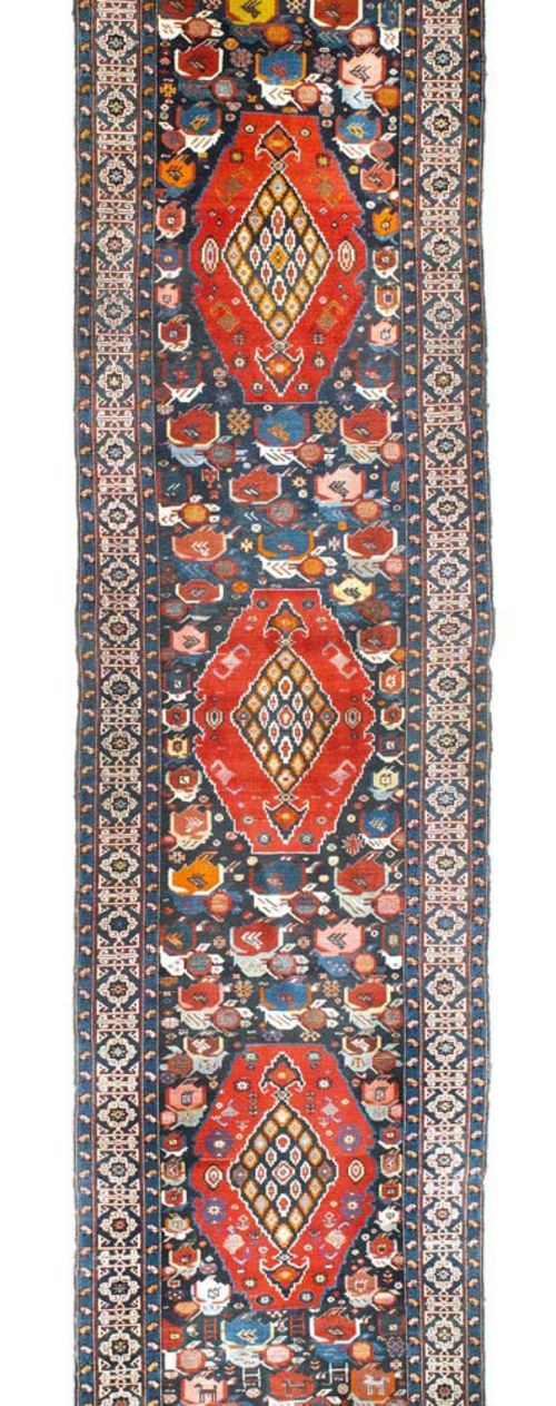 CAUCASIAN RUNNER antique.Blue central field with three red medallions, the entire carpet is geometrically patterned with stylised plants and animals, light border, good condition, 480x110 cm.