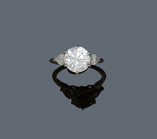 BRILLIANT-CUT DIAMOND RING. White gold 750. Elegant solitaire model, set with 1 brilliant-cut diamond of ca. 2.60 ct. ca H/VS2, flanked by two diamond drops totalling ca. 0.50 ct. Engraved mount by Boucheron. Size. ca. 50. With copy of estimate, 2006.