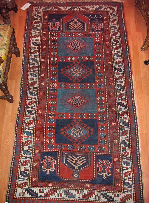 KAZAK alt.Red central field with four blue medallions, the entire carpet is geometrically patterned, white border, signs of wear, 250x115 cm.