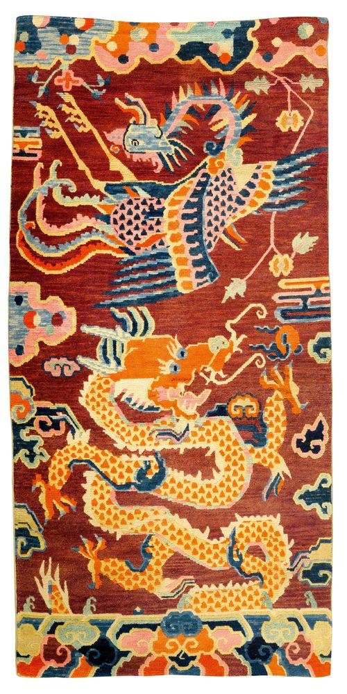 A WOOL SADDLE RUG SHOWING A DRAGON AND PHOENIX AMONG CLOUDS. Tibet, antique, 170x82 cm. Colours somewhat faded.