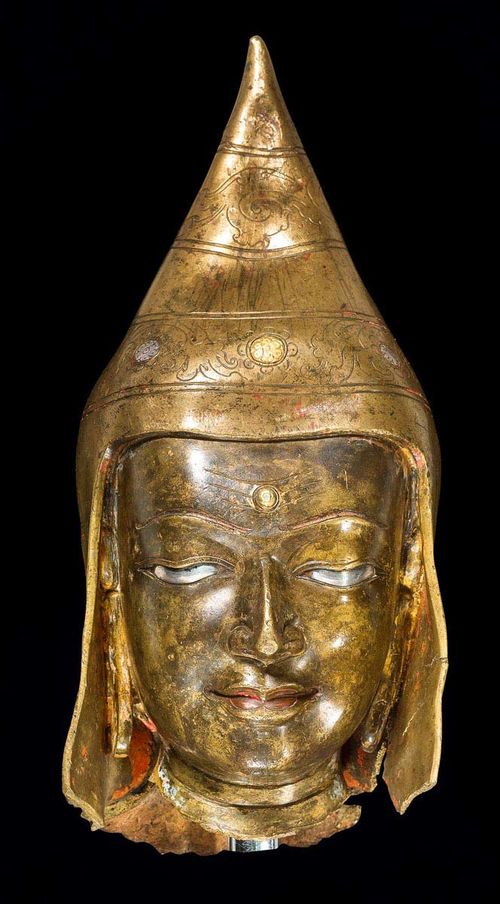 A FINE BRONZE HEAD OF A MONK. Tibet, ca. 13th c. Height 18 cm. Details in silver, gold and copper. Some dents.