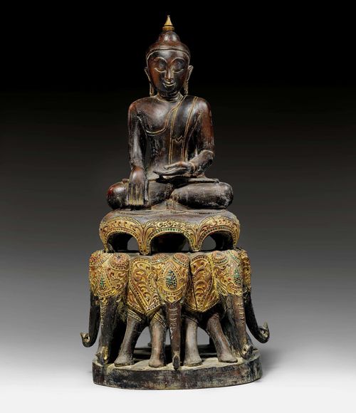 A CARVED WOODEN FIGURE OF A BUDDHA ON AN ELEPHANT PEDESTAL (GAJASANA) WITH LACQUER, GOLD AND INLAID GEMSTONES. Burma, height 100 cm. Ketumala replaced. Stone inlays lost in places.