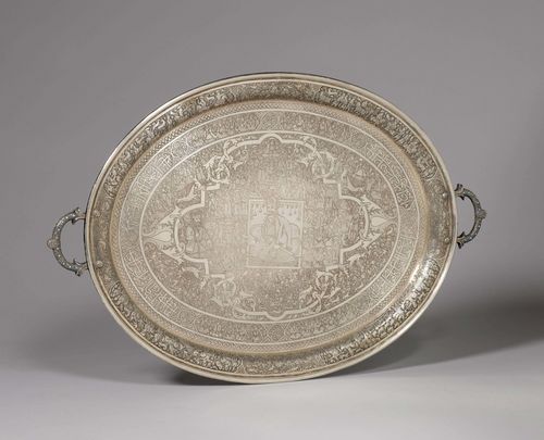 A SILVER PLATTER RICHLY ENGRAVED WITH FIGURES AMONG FLORAL AND ANIMAL MOTIFS, AND AN INSCRIPTION. Persia, Qajar, 19th c., length 42 cm, 1140g. Handles inlaid with turquoises.