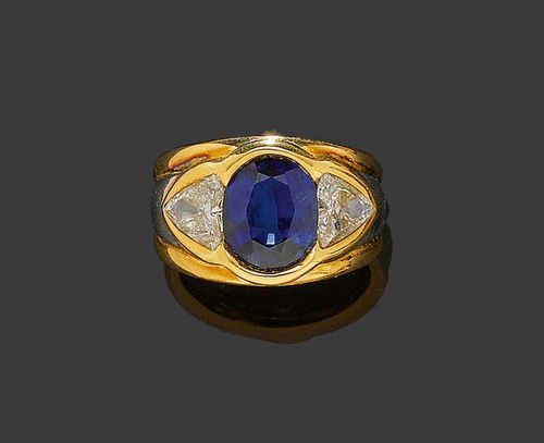 SAPPHIRE AND DIAMOND RING. Yellow gold 750. Casual-elegant band ring, the top set with 1 oval Ceylon sapphire of 5.51 ct and fine quality, flanked by 2 trilliant-cut diamonds totalling 1.84 ct. Size 57. With copy of invoice from Bucherer, January 1991.