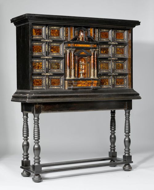 CABINET ON A STAND,Baroque, Germany or Holland, 17th century. Walnut and ebonized wood and tortoiseshell. Rectangular body, with an architectural front with a central door between 2 drawers, each flanked by 4 drawers. The door opening up into 7 drawers. Behind removable pillars: 8 secret drawers. Bronze mounts (in part later). On a later stand with turned legs. Cabinet: 137x43x85 cm. H with stand: 169 cm.