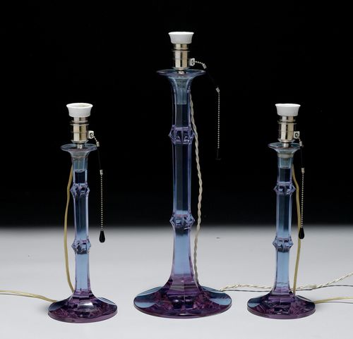LOT OF 3 CANDLESTICKS AS LAMPS,Bohemia, signed and inscribed "Alexandrit, Moser Carlsbad". Crystal glass. 7-sided glass shaft, protruding lip and round foot. H 54 and 40 cm. Fitted for electricity. Chip on foot.