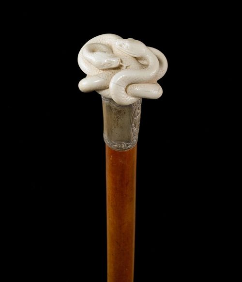 WALKING STICK WITH 2 SNAKES.Ivory grip, carved all-around with 2 intertwined snakes. Malacca wood stick with brass tip. L 91 cm.