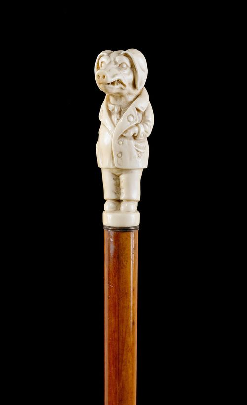 WALKING STICK WITH A SCULPTED PIG.Ivory, carved all-around. Grip designed as a pig wearing gentleman's clothes. Reddish Malacca wood stick with brass tip. L 98.5 cm.