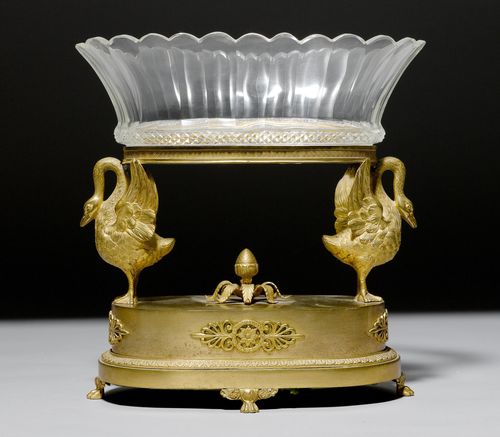 TABLE CENTREPIECE "AUX CYGNES",Empire/Restoration, Paris, ca. 1818/30. Gilt bronze and cut glass (glass bowl after 1900). Oval, finely cut bowl borne by 2 swans. Matching base on fine paw feet. 29 x 17 x 29.5 cm. Provenance: - from a private collection, Suisse romande.