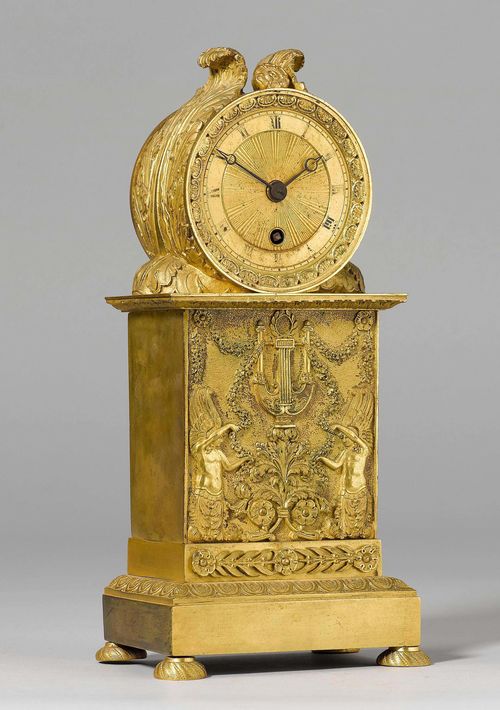 MANTEL CLOCK,Restoration, Paris. Gilt bronze. Cylindrical case on a rectangular plinth and spherical feet. Decorated with 2 nymphs with a lyre, garlands and tendrils. Engraved brass dial. Parisian movement. H 28 cm. Pendulum missing. Requires some restoration. Provenance: - from the collection of the Marquis and the Marquise de Amodio y Moya, Hôtel particulier, 93 rue de l'Université, Paris (formerly de La Rochefoucauld).