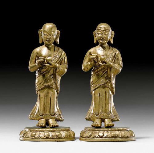ANANDA AND KASYAPA.Sino-Tibetan, c. 1800, H 9.5 cm. Bronze, the eyes cold painted. The two favourite disciples of the Buddha, the young Ananda and the elder Kasyapa, each standing on a round lotus pedestal and holding an alms bowl in his hand. The pedestals cast separately.