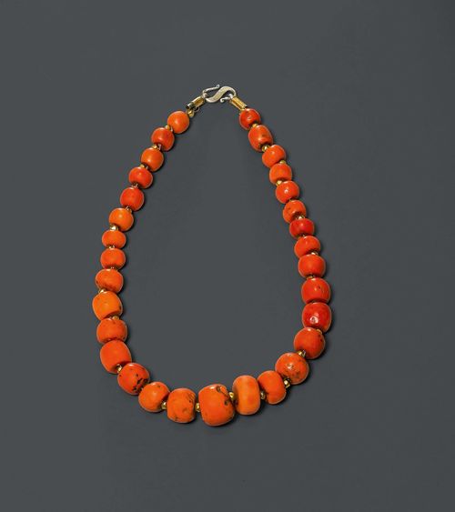 NECKLACE.Tibet, L 51 cm. 31 round corals are each strung between two gilded metal beads. S-shaped closure.