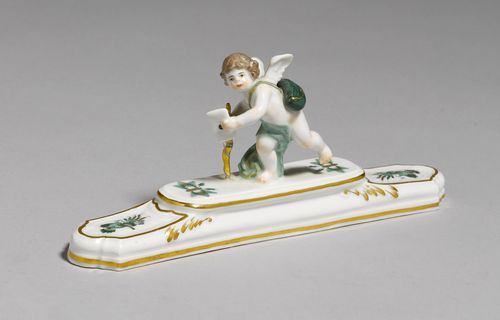 PAPERWEIGHT WITH PUTTO AS THE MESSENGER BEARING A LOVE LETTER,Meissen, ca. 1900. Rectangular base with "Oriental" decoration. Underglaze blue sword mark with pommels, model number 1645, press number. L 19.5 cm.