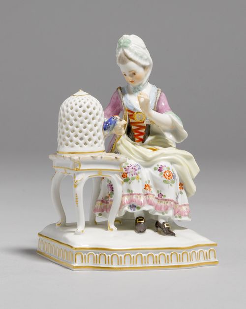 THE SENSE OF TOUCH FROM A SERIES OF THE FIVE SENSES,Meissen, model by Victor Acier, after 1948. A Rococo lady seated at a table with a bird cage with a canary pecking her finger. Underglaze blue sword mark, model number E. 4 incised, press number. H 14.5 cm.